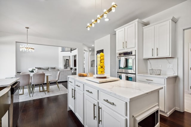 kitchen with dark wood-style floors, a notable chandelier, stainless steel double oven, built in microwave, and dishwashing machine