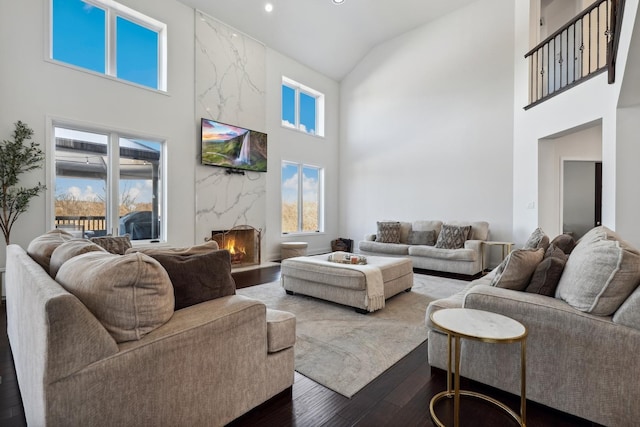 living room featuring high vaulted ceiling, dark wood-style flooring, and a high end fireplace