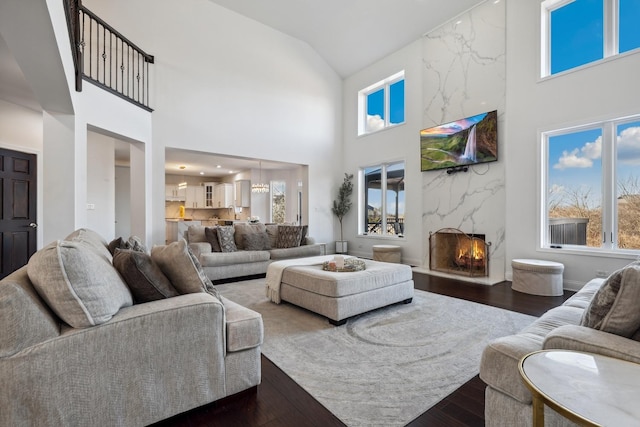 living room with a fireplace, dark wood finished floors, and a towering ceiling