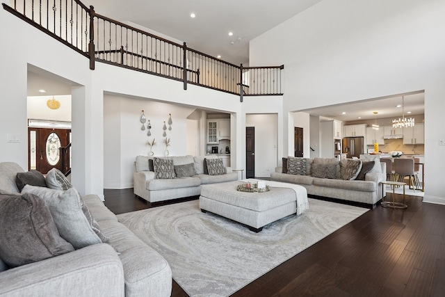 living area featuring baseboards, dark wood finished floors, a towering ceiling, and recessed lighting