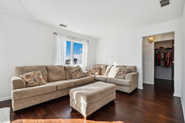 living room with dark wood-style floors, visible vents, and baseboards