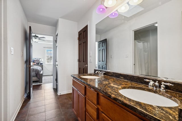 ensuite bathroom with double vanity, tile patterned flooring, baseboards, and a sink