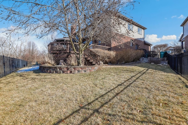 back of property with a fenced backyard, a yard, stairway, and a wooden deck