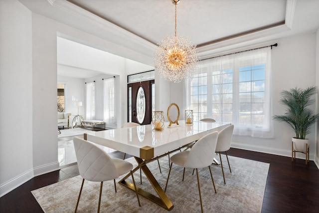 dining area featuring a tray ceiling, dark wood finished floors, and baseboards