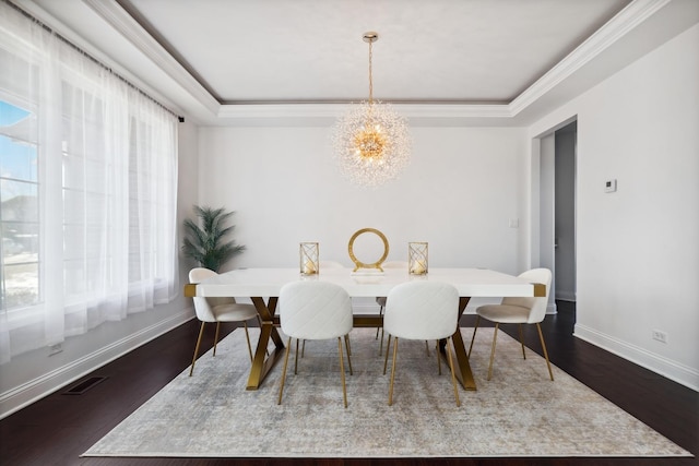 dining space with visible vents, a raised ceiling, wood finished floors, and a chandelier