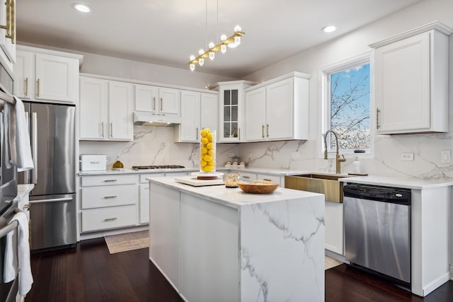 kitchen with stainless steel appliances, a sink, white cabinets, and under cabinet range hood