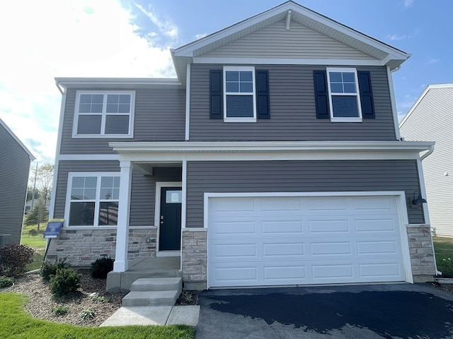 view of front facade featuring stone siding, driveway, and an attached garage