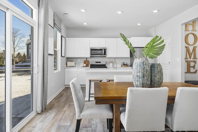 dining area with sink and light wood-type flooring