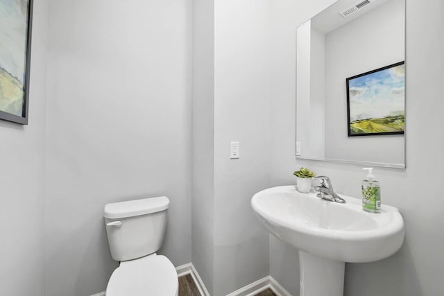 half bath featuring visible vents, baseboards, and toilet