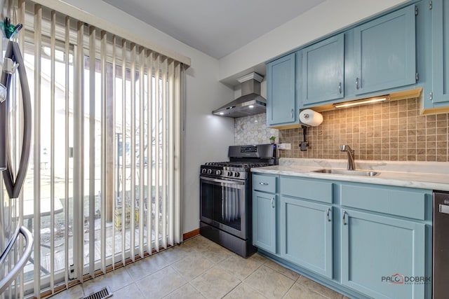 kitchen featuring wall chimney exhaust hood, blue cabinetry, stainless steel appliances, and sink