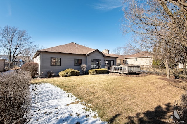 rear view of house with a wooden deck and a lawn