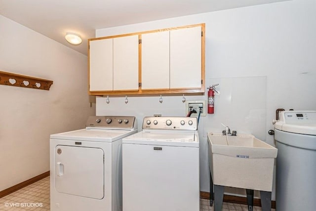 washroom featuring separate washer and dryer, a sink, baseboards, cabinet space, and light floors