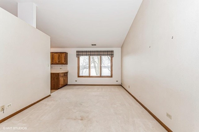 unfurnished living room with visible vents, baseboards, and light colored carpet