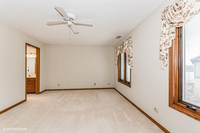 spare room with baseboards, a ceiling fan, visible vents, and light colored carpet