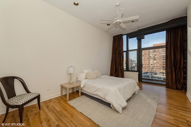 bedroom with access to exterior, light hardwood / wood-style flooring, floor to ceiling windows, and ceiling fan