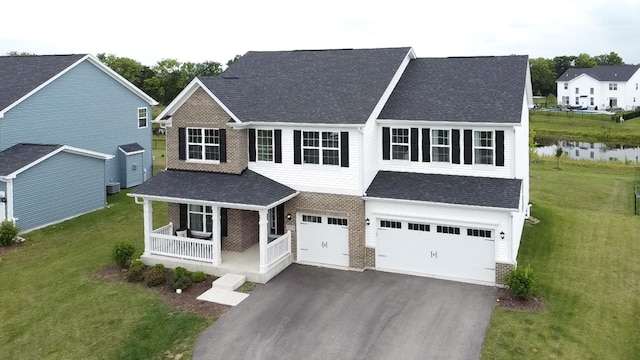 view of front of home featuring a garage, covered porch, and a front lawn