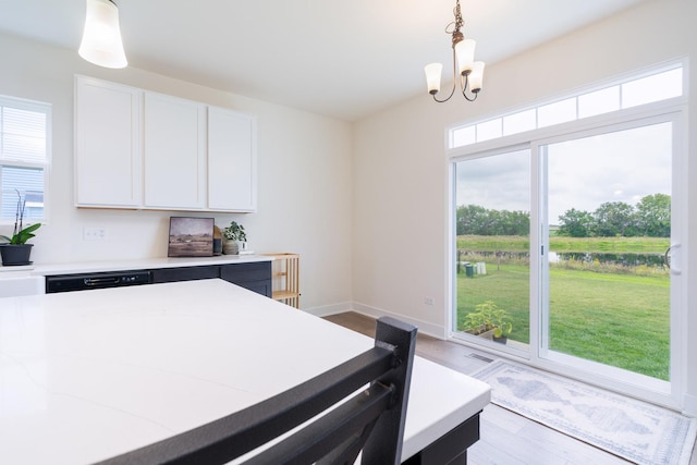 kitchen with hanging light fixtures, dishwasher, a notable chandelier, light stone countertops, and white cabinets