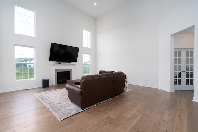 living room featuring french doors, light hardwood / wood-style floors, and a high ceiling