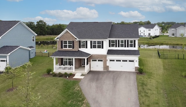 view of front of property featuring a porch, a garage, a front yard, and a water view