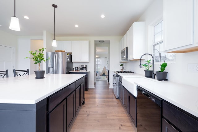 kitchen with white cabinetry, hanging light fixtures, light wood-type flooring, and appliances with stainless steel finishes