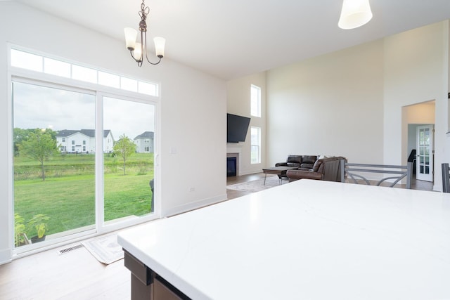 kitchen featuring hanging light fixtures, a notable chandelier, light hardwood / wood-style floors, and a high ceiling