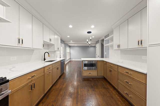 kitchen with sink, appliances with stainless steel finishes, light stone countertops, white cabinets, and kitchen peninsula