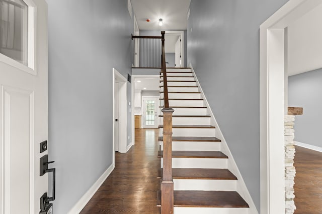 staircase with wood-type flooring and a high ceiling