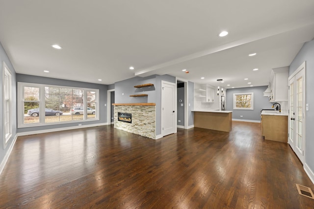 unfurnished living room with dark hardwood / wood-style flooring, sink, and a wealth of natural light