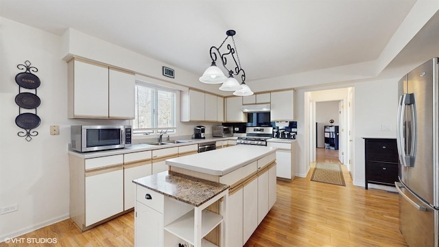 kitchen featuring under cabinet range hood, stainless steel appliances, a kitchen island, a sink, and open shelves