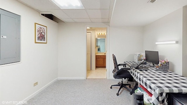 carpeted office with a drop ceiling, electric panel, and baseboards