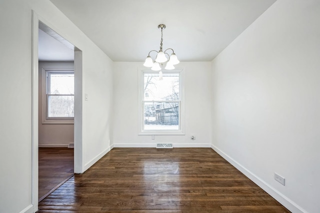 unfurnished room featuring dark hardwood / wood-style flooring and an inviting chandelier