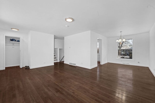 unfurnished living room with dark wood-type flooring and a notable chandelier