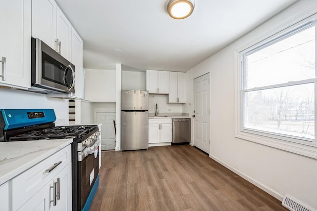 kitchen with white cabinetry, appliances with stainless steel finishes, and light stone counters