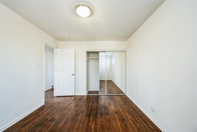 unfurnished bedroom featuring dark hardwood / wood-style flooring and a closet