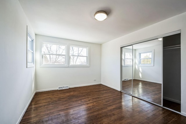 unfurnished bedroom featuring dark wood-type flooring and a closet