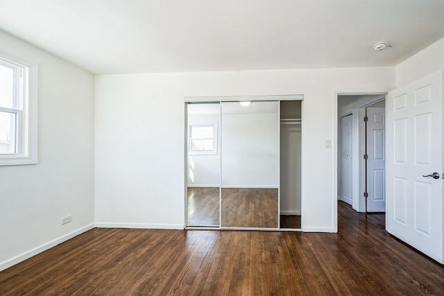 unfurnished bedroom with dark hardwood / wood-style flooring and a closet