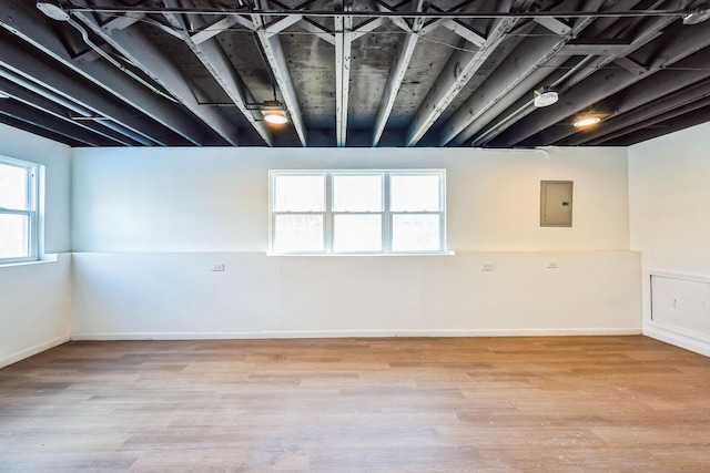 basement with light hardwood / wood-style flooring and electric panel