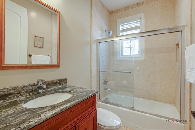 full bath featuring vanity, toilet, and combined bath / shower with glass door