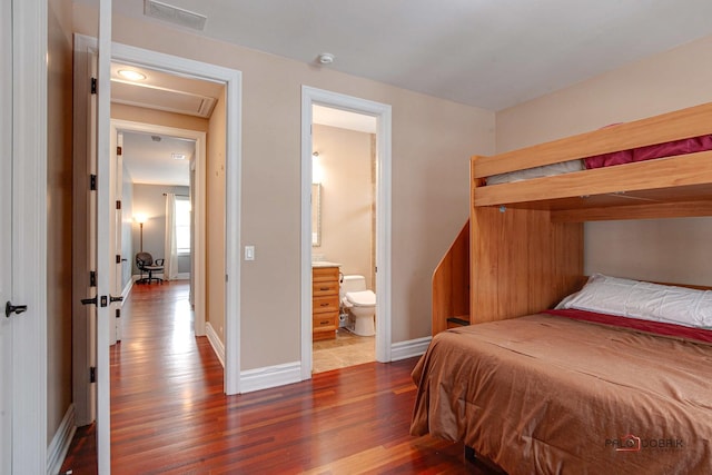 bedroom with wood finished floors, visible vents, ensuite bathroom, and baseboards