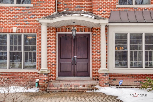 doorway to property featuring a standing seam roof and brick siding