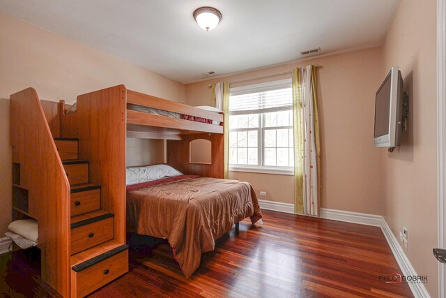 bedroom featuring visible vents, baseboards, and wood finished floors