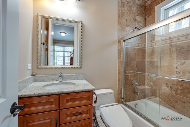 bathroom with combined bath / shower with glass door, toilet, and vanity