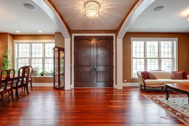 entryway featuring plenty of natural light, arched walkways, and wood finished floors