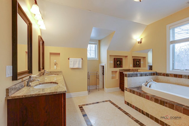 bathroom featuring lofted ceiling, a sink, double vanity, baseboards, and a bath