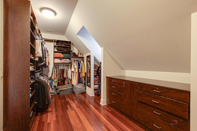 walk in closet with dark wood-type flooring and vaulted ceiling