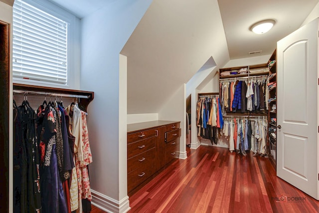 spacious closet featuring dark wood-style floors, visible vents, and vaulted ceiling