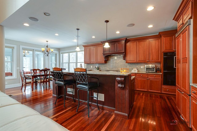 kitchen with a kitchen bar, dark wood finished floors, tasteful backsplash, and a center island