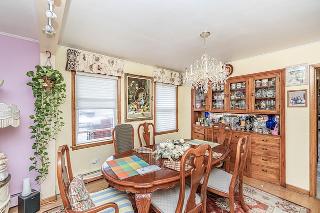 dining room with baseboard heating, ornamental molding, hardwood / wood-style floors, and a notable chandelier