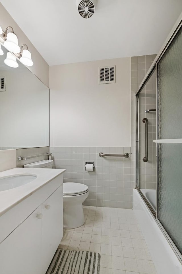 full bathroom with tile patterned flooring, visible vents, vanity, and tile walls