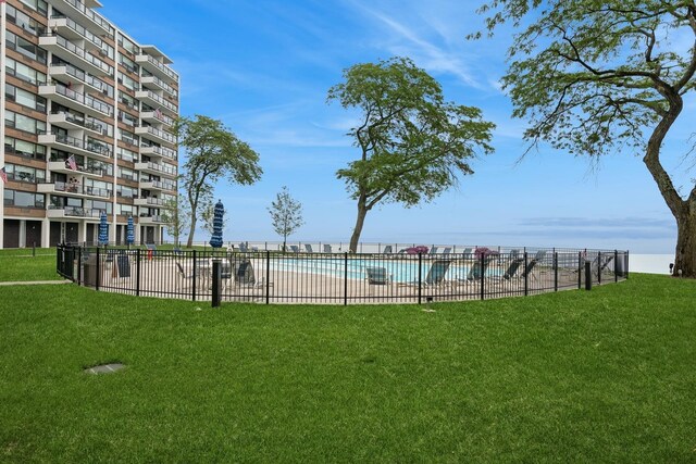 view of property's community with a pool, a yard, and fence